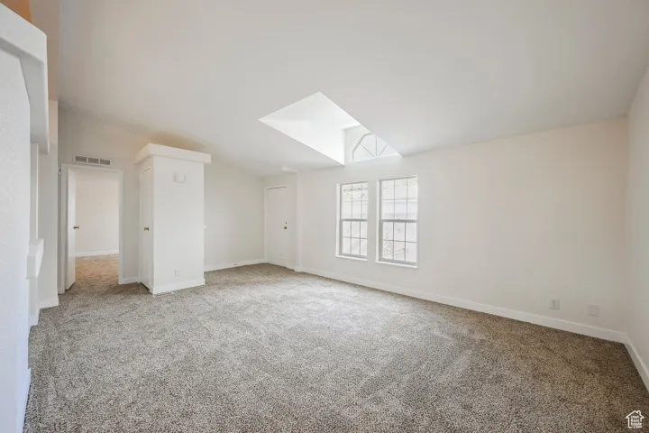 Bonus room with light colored carpet and vaulted ceiling