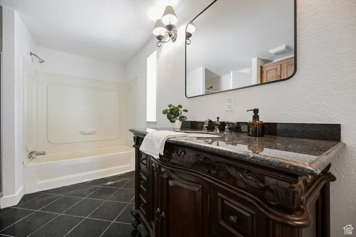 Bathroom featuring  shower combination, vanity, and tile patterned flooring