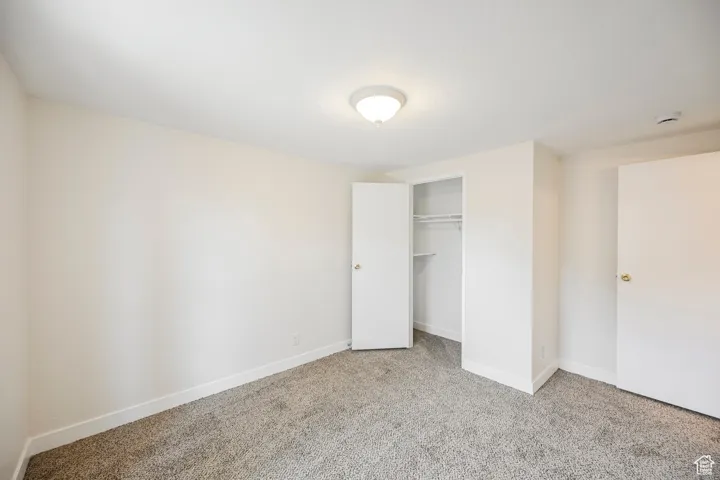 Unfurnished bedroom with a closet and light colored carpet