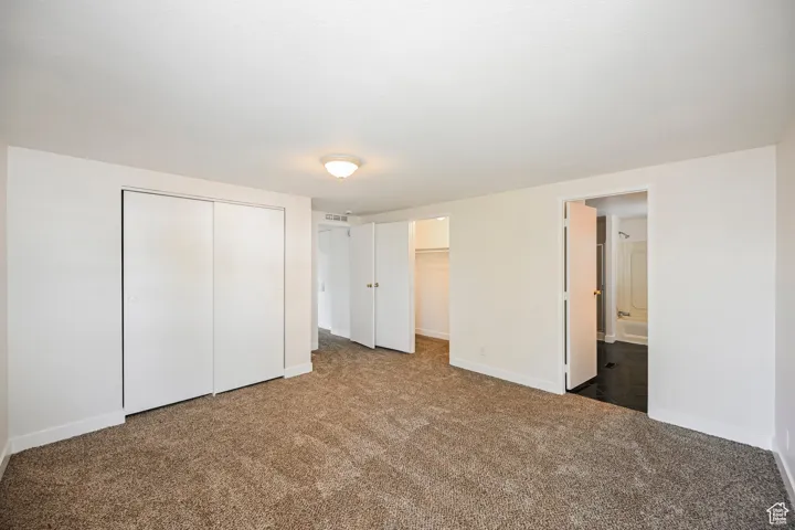 Unfurnished bedroom featuring ensuite bath and carpet
