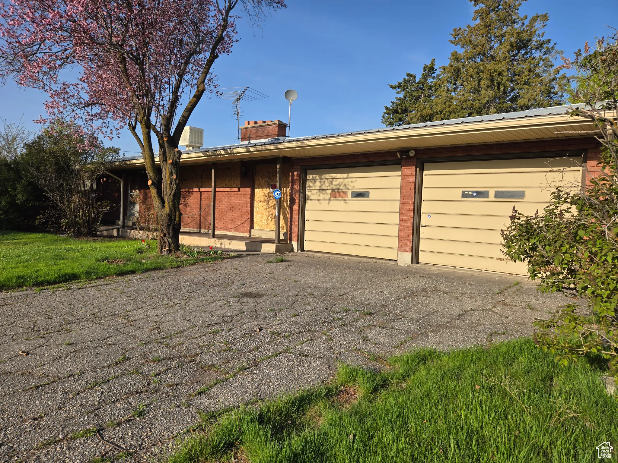 Ranch-style home with brick siding, a chimney, an attached garage, and aphalt driveway