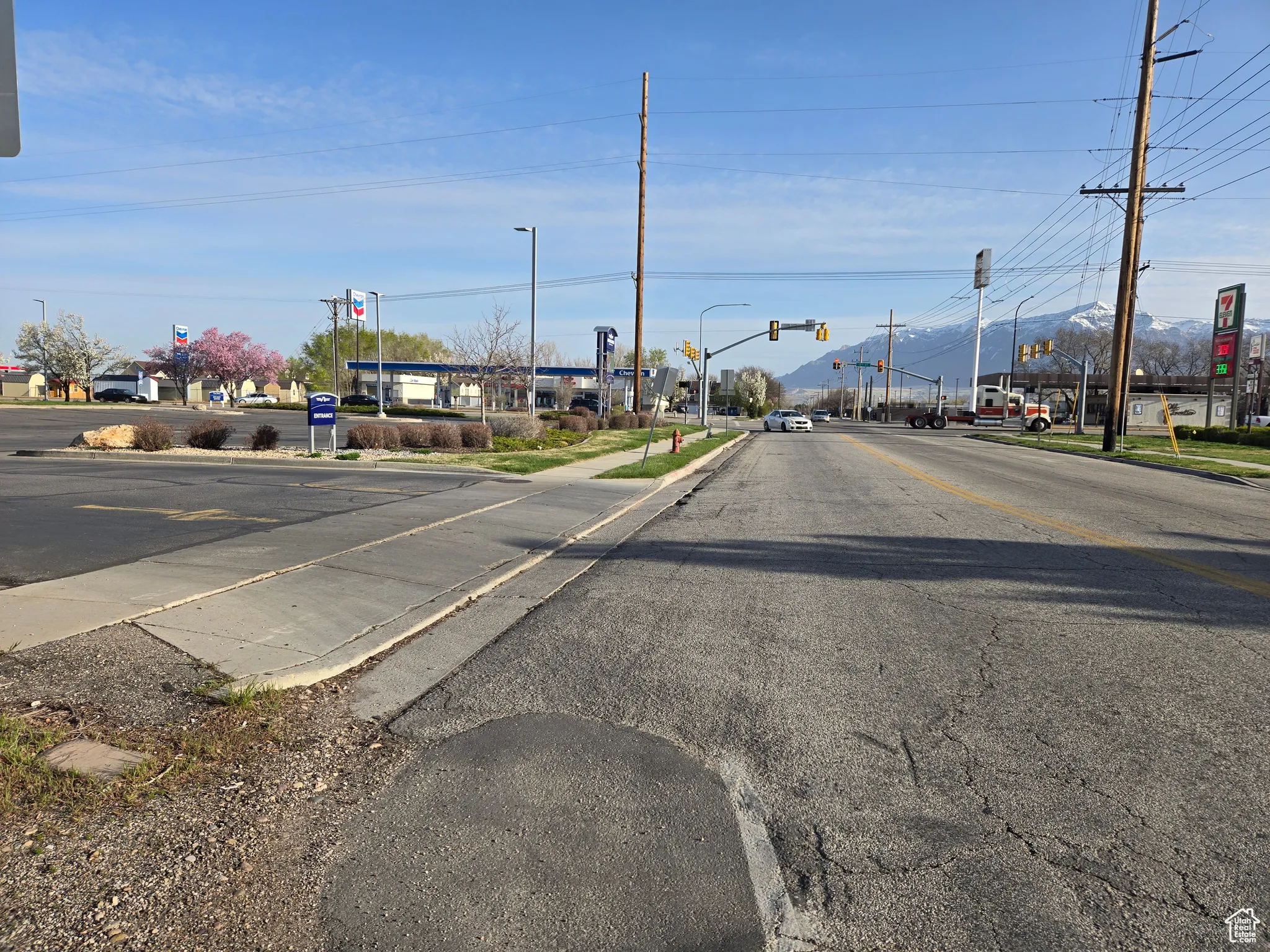 View of street featuring street lights, traffic lights, sidewalks, and curbs