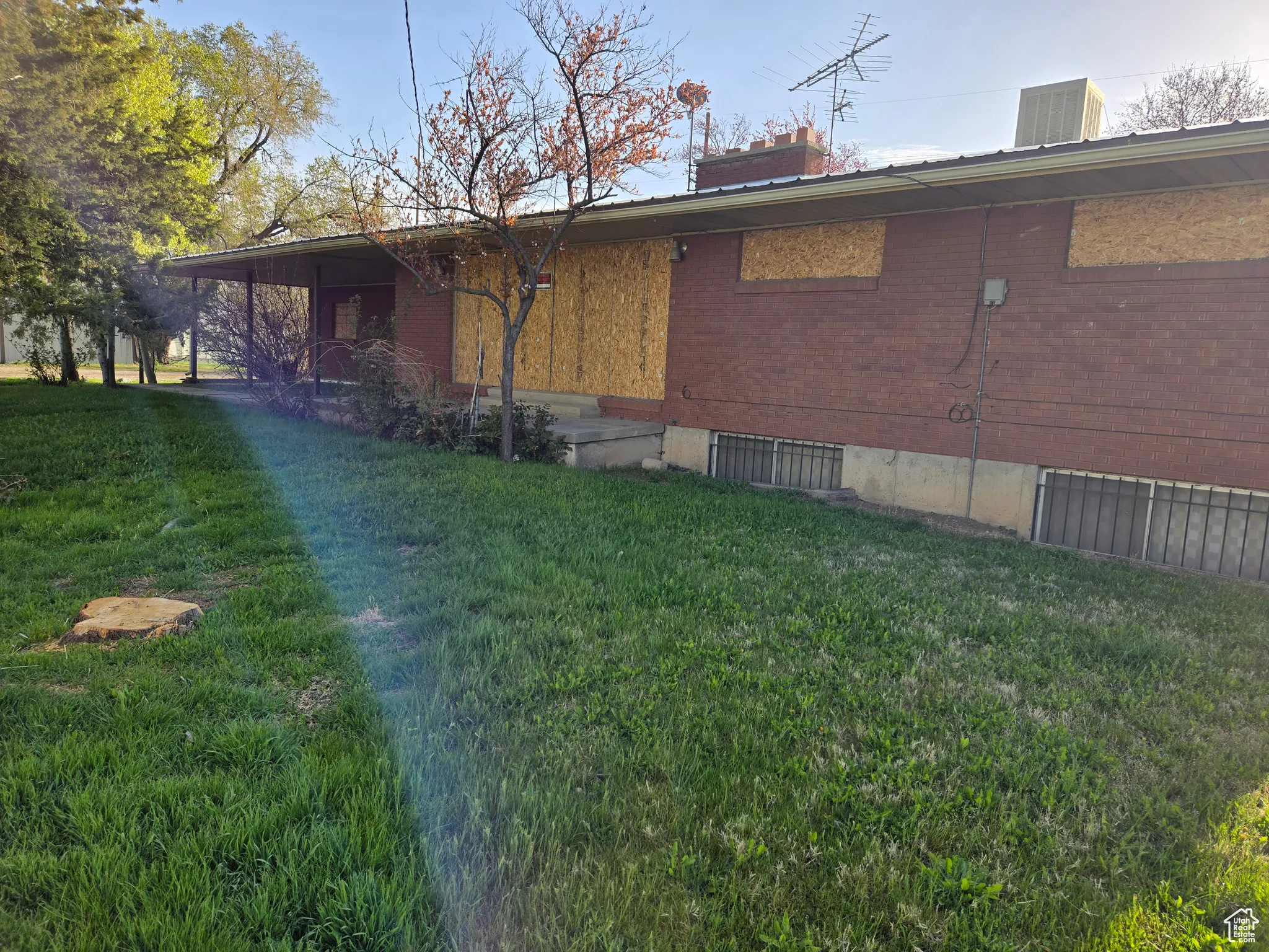 View of side of home with brick siding, a chimney, and a lawn