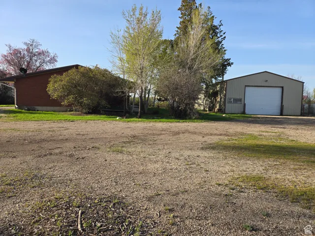 View of yard featuring a garage, driveway, and an outbuilding