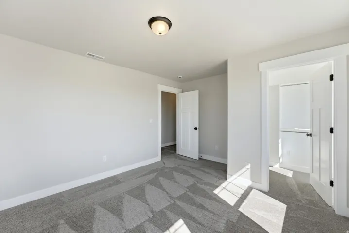Unfurnished bedroom with dark carpet and ensuite bath