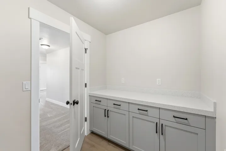 Bar featuring gray cabinets, light wood finished floors, and light stone counters