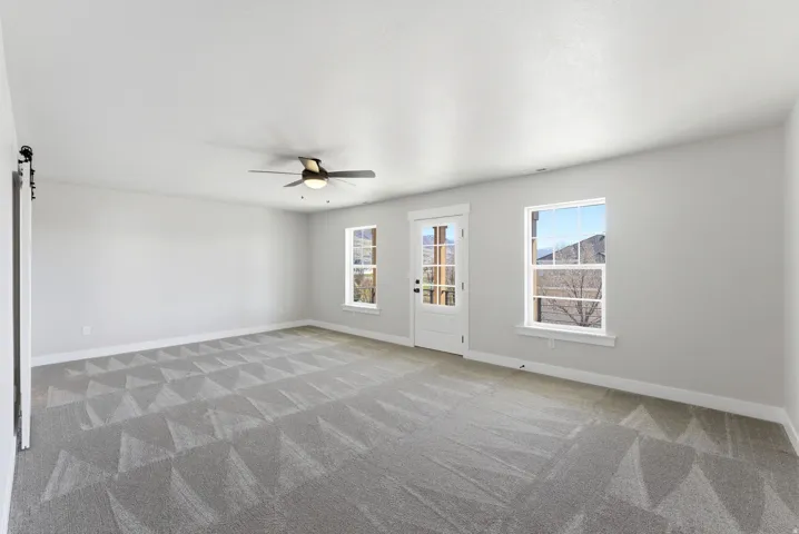 Spare room featuring a barn door, a ceiling fan, and light colored carpet