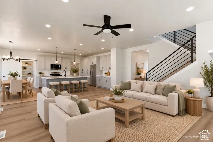 Open-concept living space featuring wood-finish flooring, a modern kitchen with light cabinetry, and a dining area