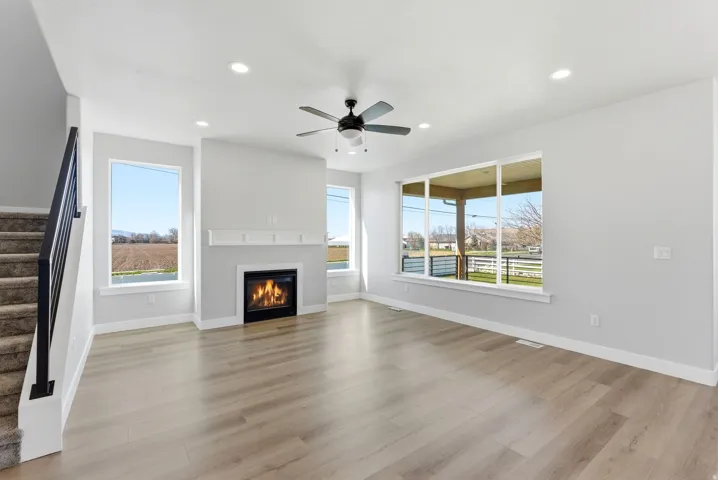 Unfurnished living room with a glass covered fireplace, a ceiling fan, recessed lighting, and light wood-type flooring