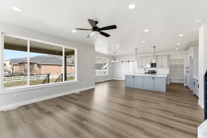 Unfurnished living room featuring a chandelier, a ceiling fan, and light wood-style floors