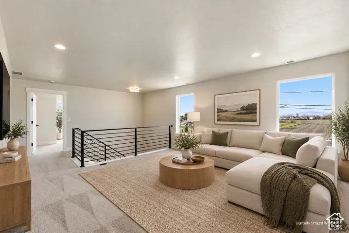 Open concept living space with recessed lighting, carpeted flooring, and a modern horizontal bar railing