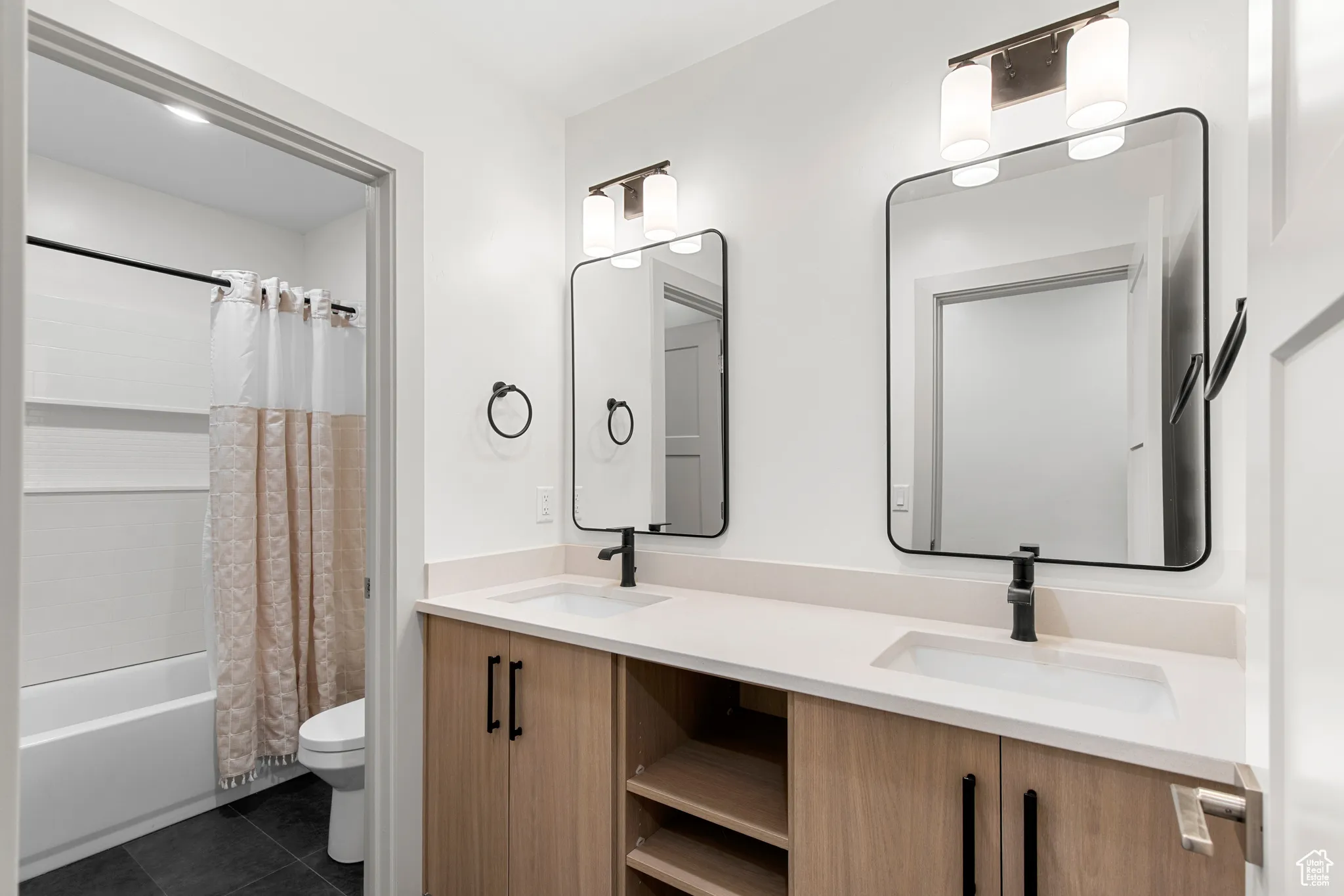 Full bath with shower / bath combo, double vanity, and dark tile patterned flooring