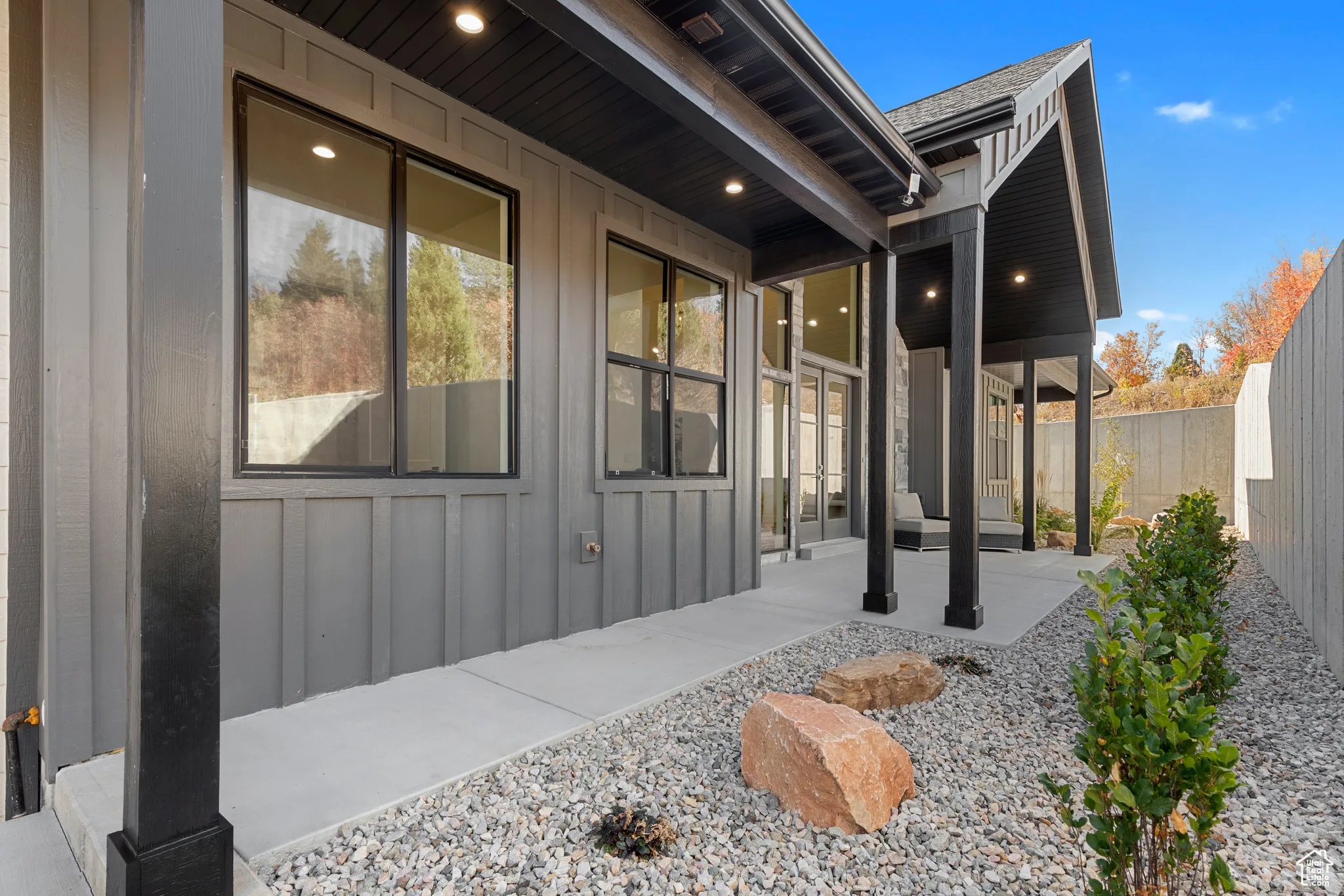 View of side of home featuring board and batten siding, a fenced backyard, and a patio area