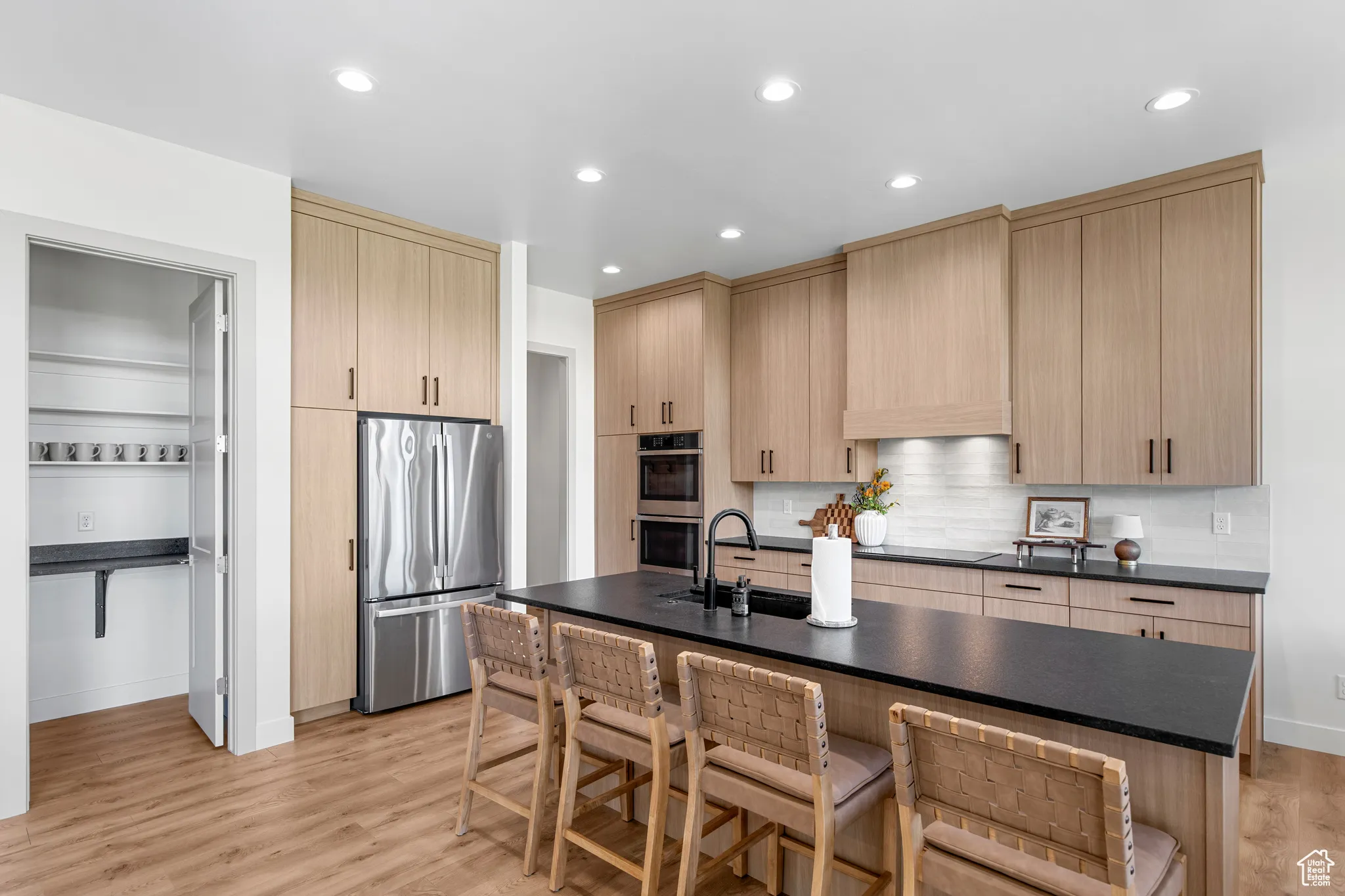 Kitchen with light brown cabinets, stainless steel appliances, light wood-type flooring, and recessed lighting