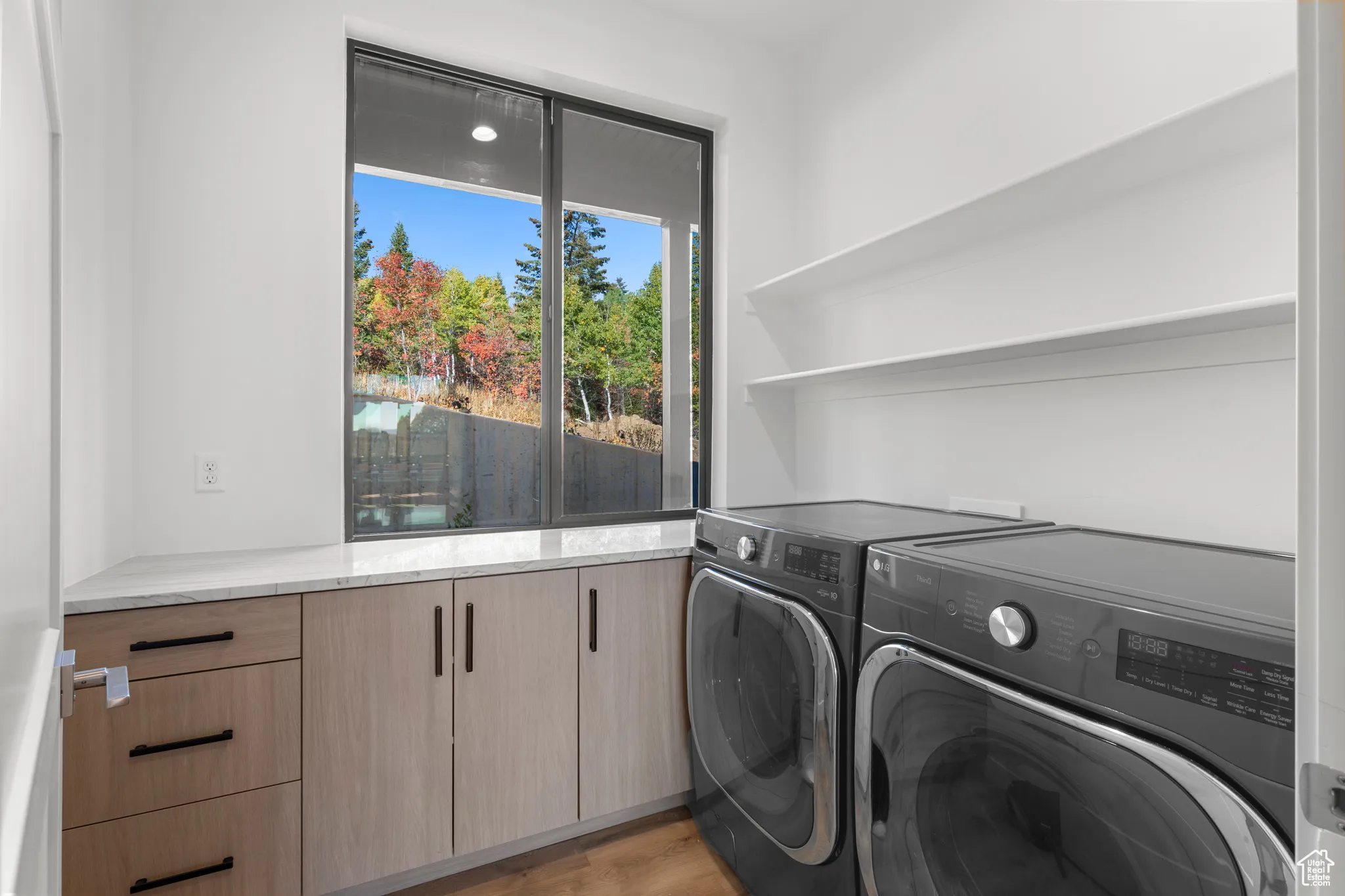 Laundry room with washing machine and dryer and light wood-type flooring