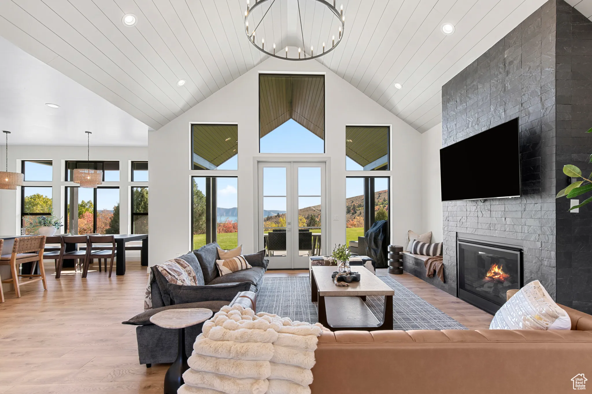 Living area featuring light wood-type flooring, a fireplace, a chandelier, recessed lighting, and high vaulted ceiling