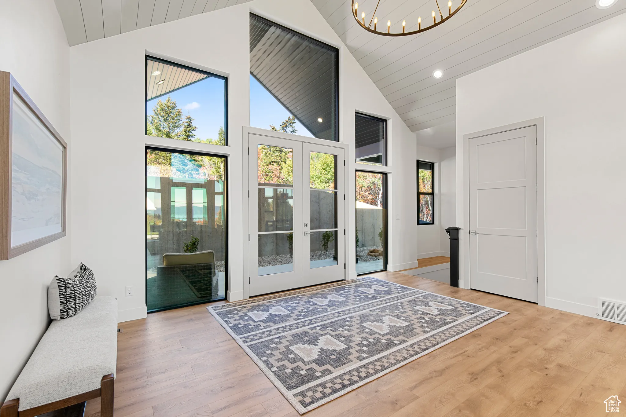 Doorway featuring french doors, high vaulted ceiling, wood finished floors, recessed lighting, and a chandelier