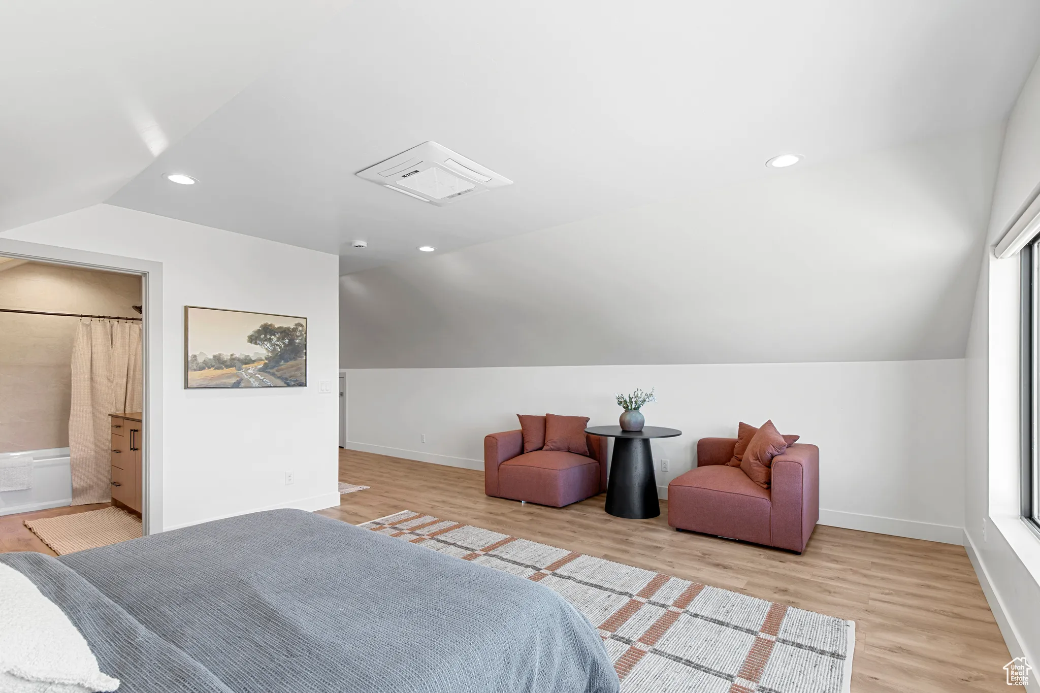 Bedroom with vaulted ceiling, light wood finished floors, recessed lighting, and connected bathroom
