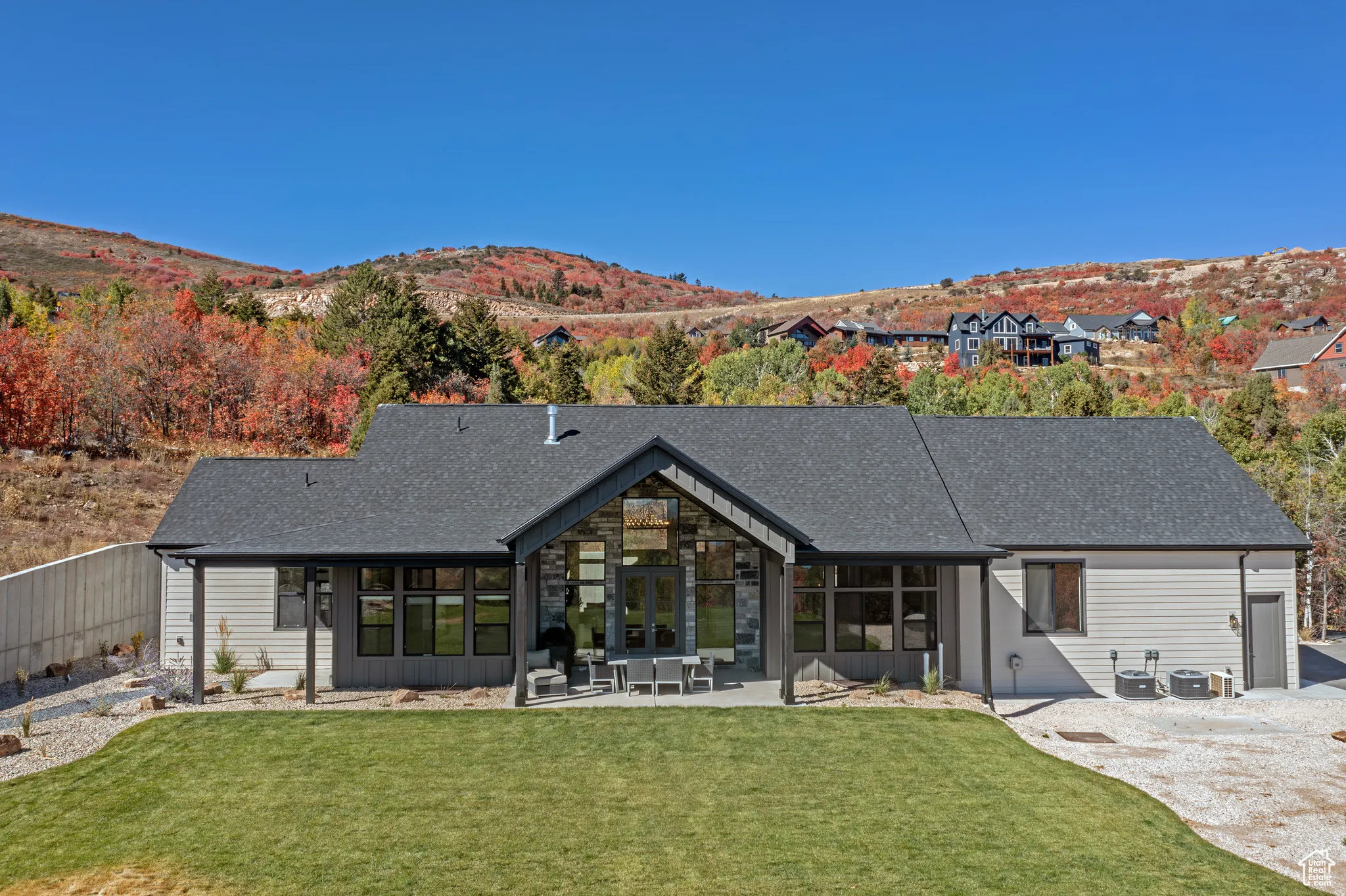 Back of property with a patio, a mountain view, a shingled roof, and a lawn