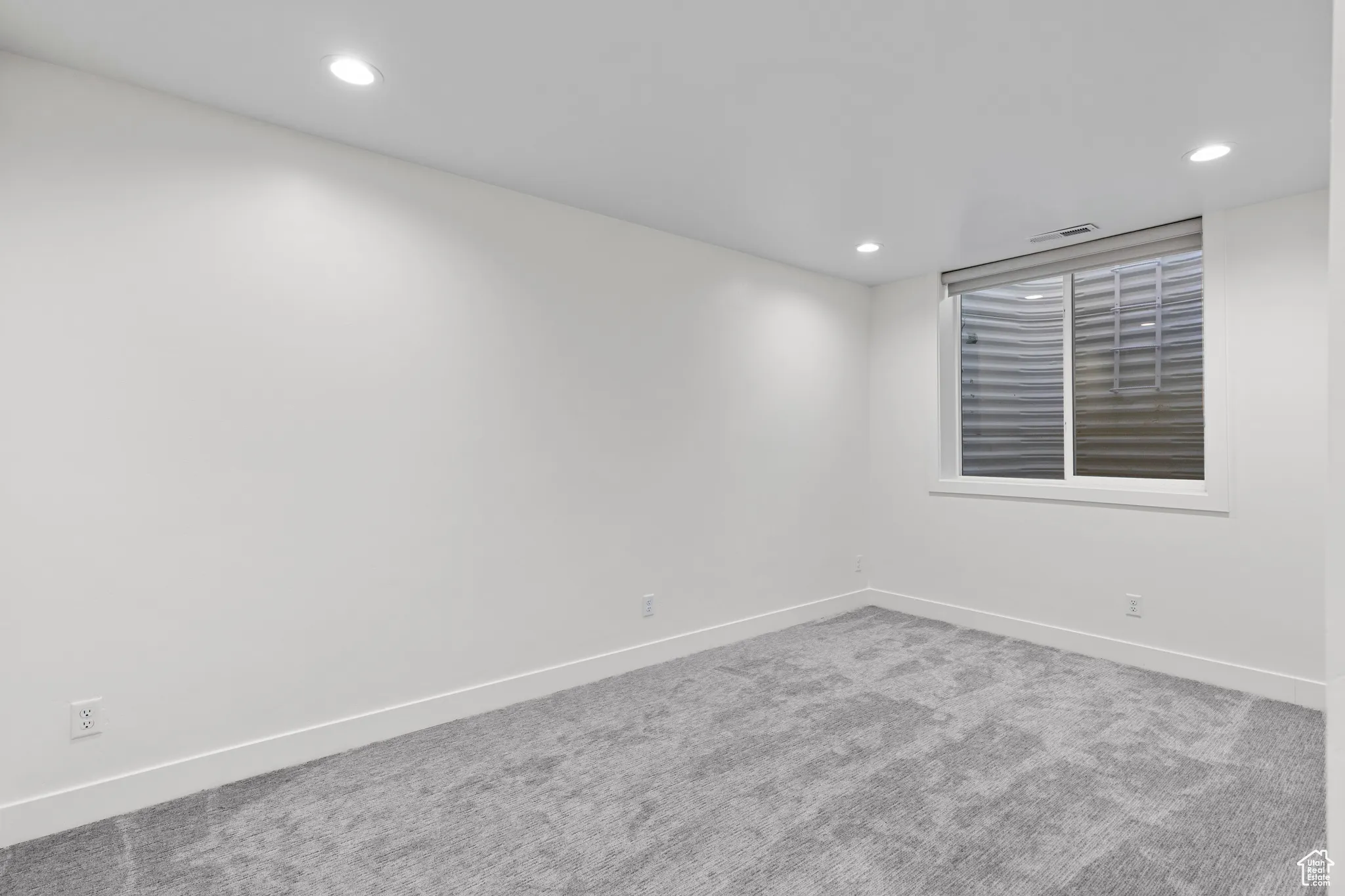 Carpeted empty room with baseboards and recessed lighting