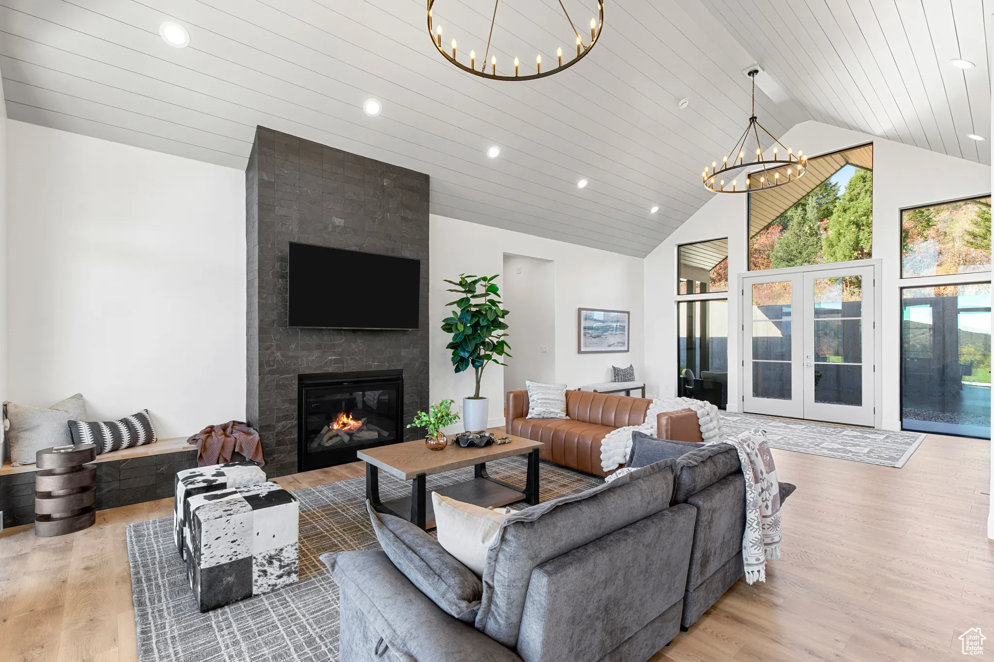 Living room with french doors, high vaulted ceiling, light wood-style floors, recessed lighting, and a large fireplace