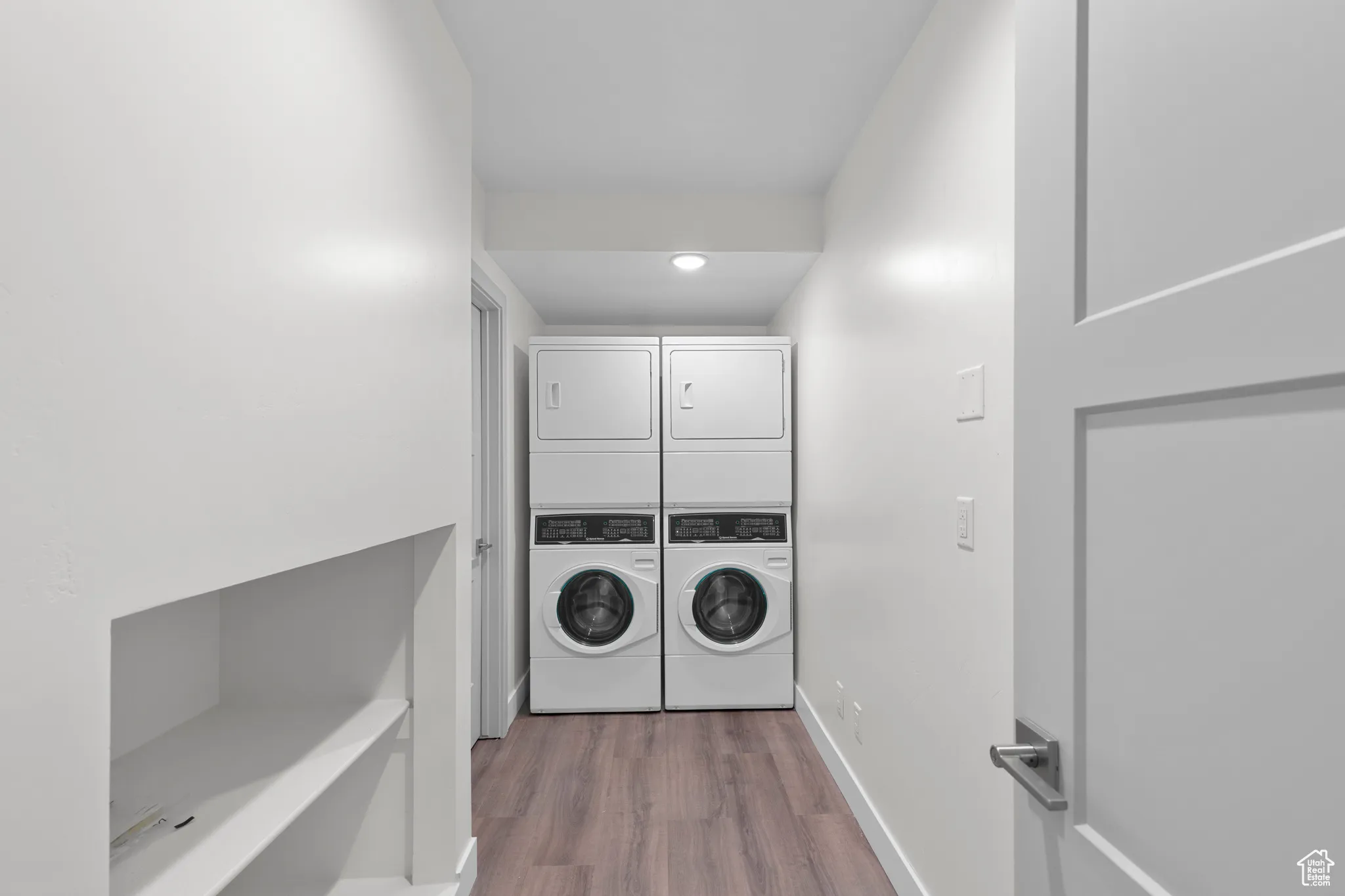 Laundry area featuring dark wood-style flooring, stacked washing machine and dryer, and recessed lighting