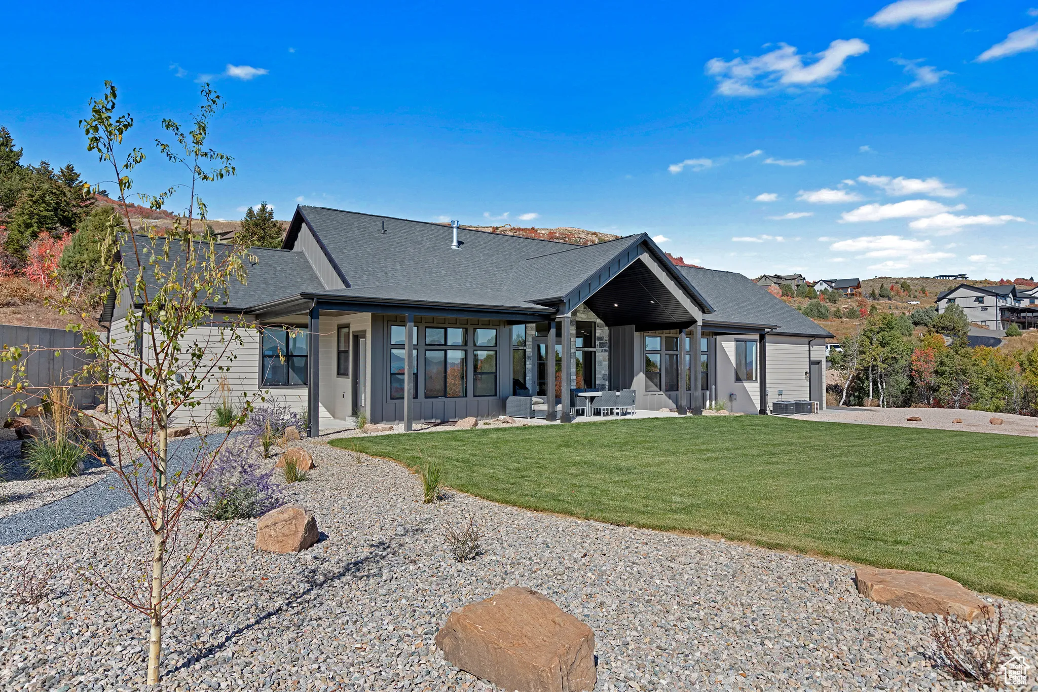 Rear view of house with a patio area, a yard, roof with shingles, and board and batten siding