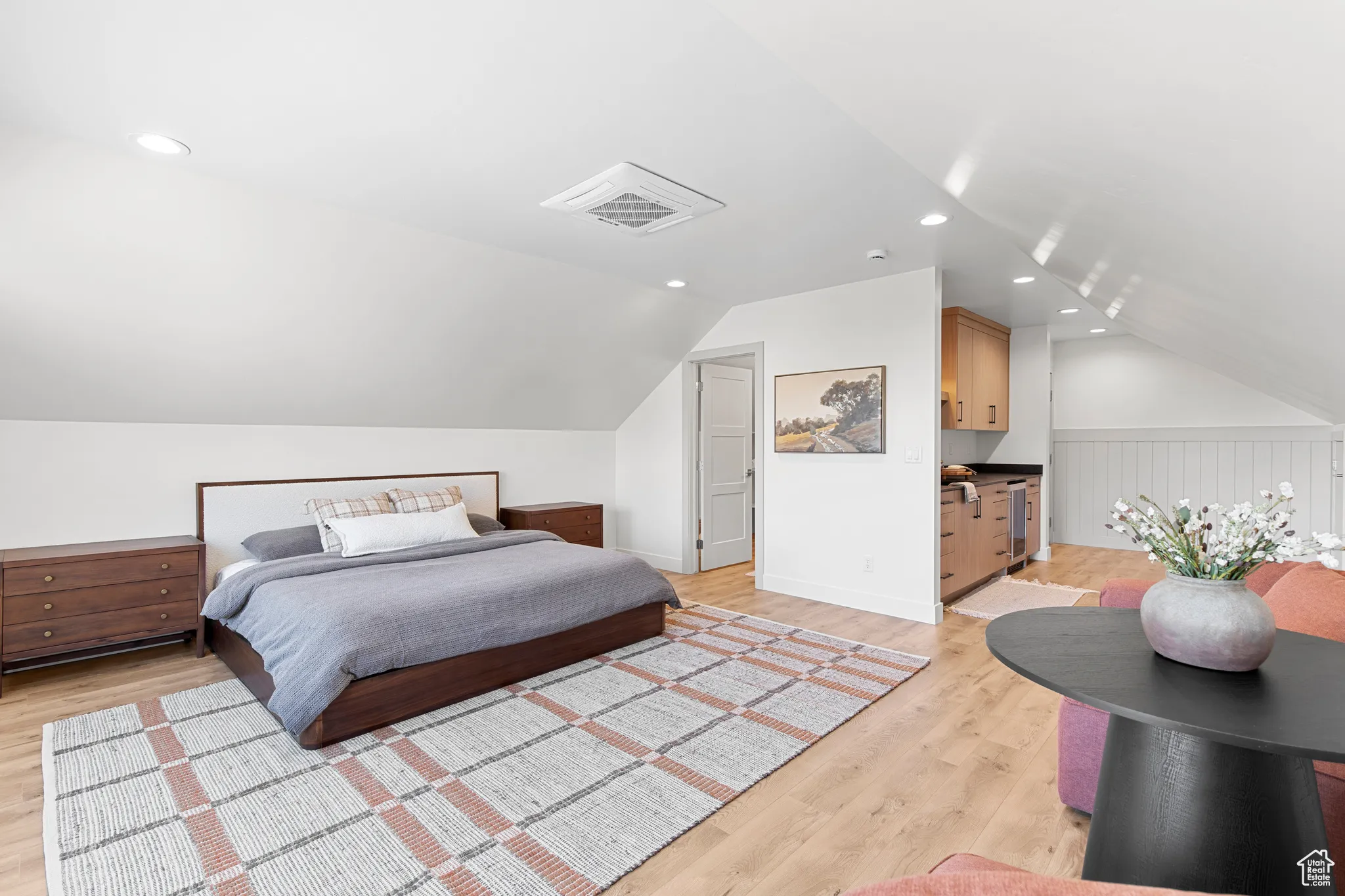 Bedroom featuring light wood finished floors, vaulted ceiling, recessed lighting, and beverage cooler