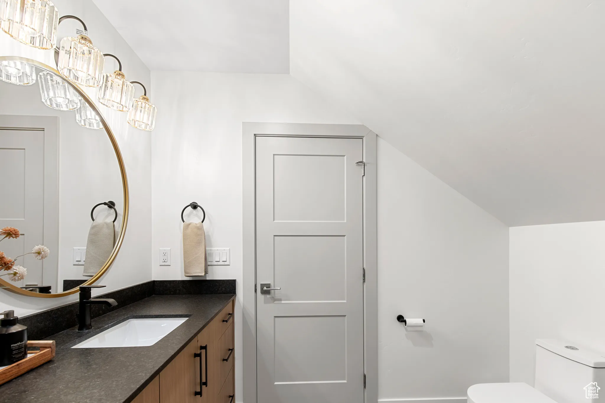 Bathroom featuring vanity, a chandelier, and lofted ceiling