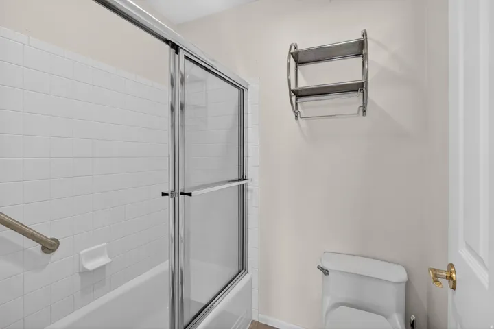 Bathroom featuring toilet and bath / shower combo with glass door