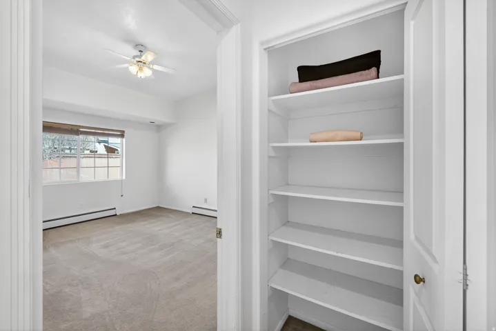Spare room featuring light colored carpet, a baseboard radiator, and a ceiling fan