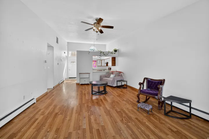 Living area with baseboard heating, light wood finished floors, and ceiling fan