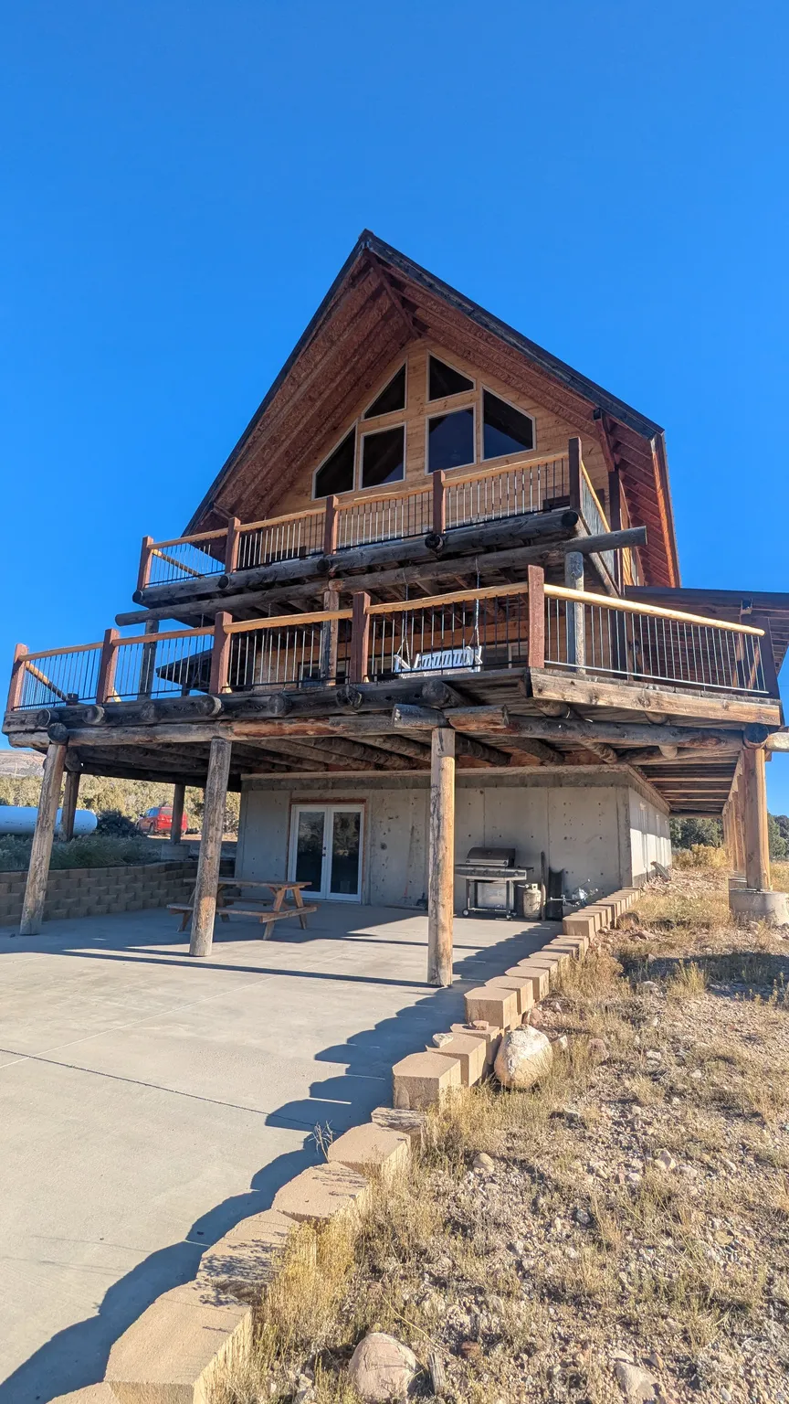 Back of property featuring a wooden deck, a patio area, and driveway