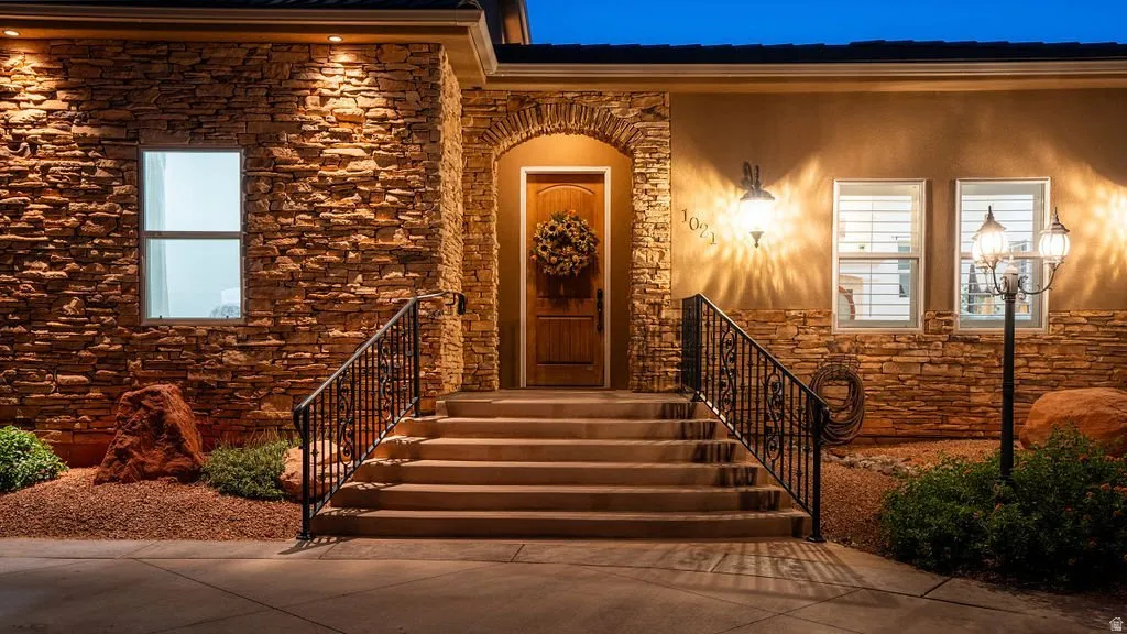 Stacked stone and warm light at the front entry after dark.