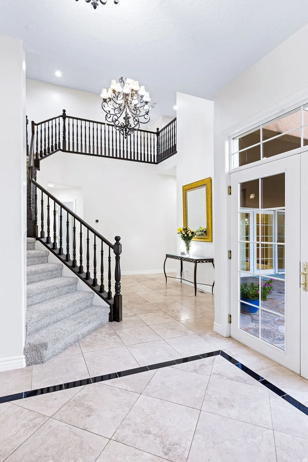 Two-story entry with curved iron stair and travertine floors.