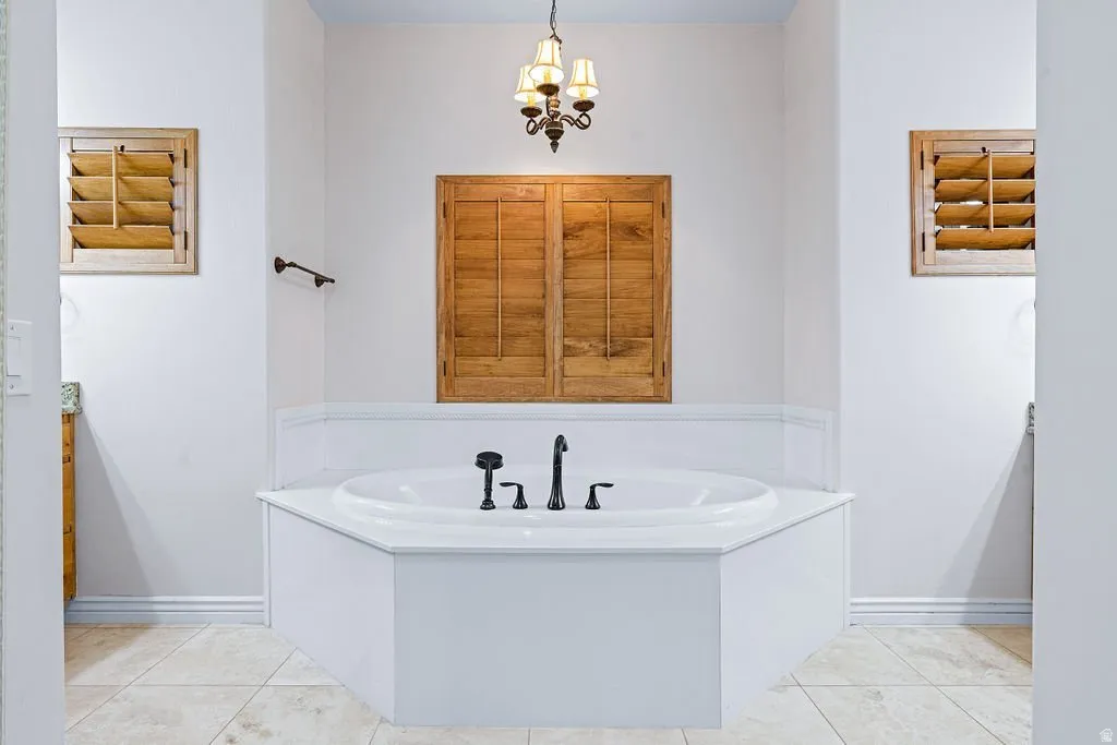Freestanding soaking tub beneath shuttered windows.