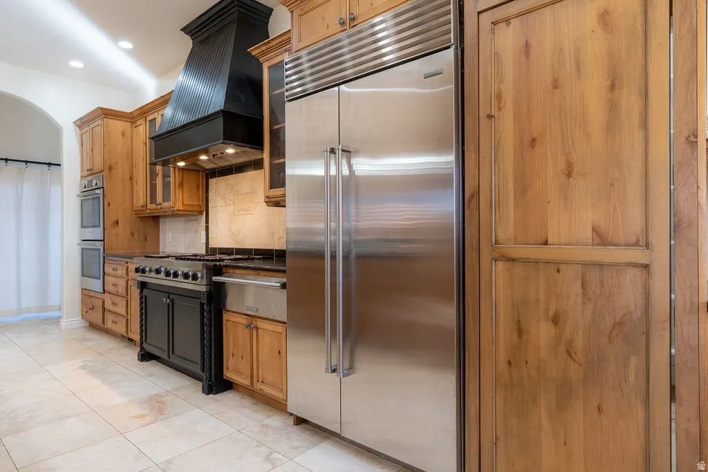 Viking six-burner cooktop, double ovens, built-in refrigeration, and custom knotty alder — with a walk-in pantry hidden behind a matching cabinet door.