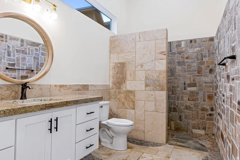 Full bath with walk-in tile shower and stone counters.