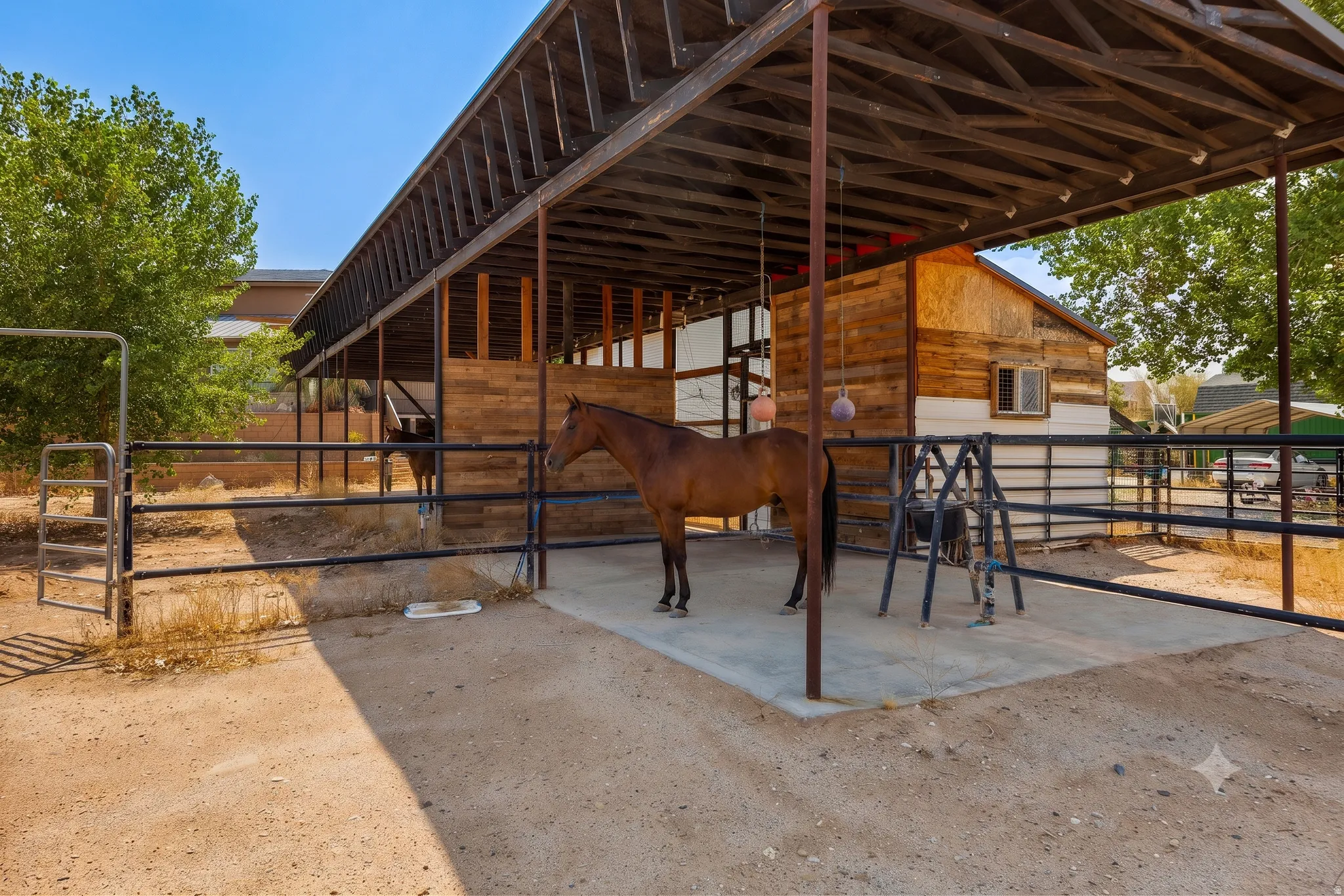 Concrete-padded covered pen with pipe panel corral and stall toys already hanging. Turn horses out the day you close.
