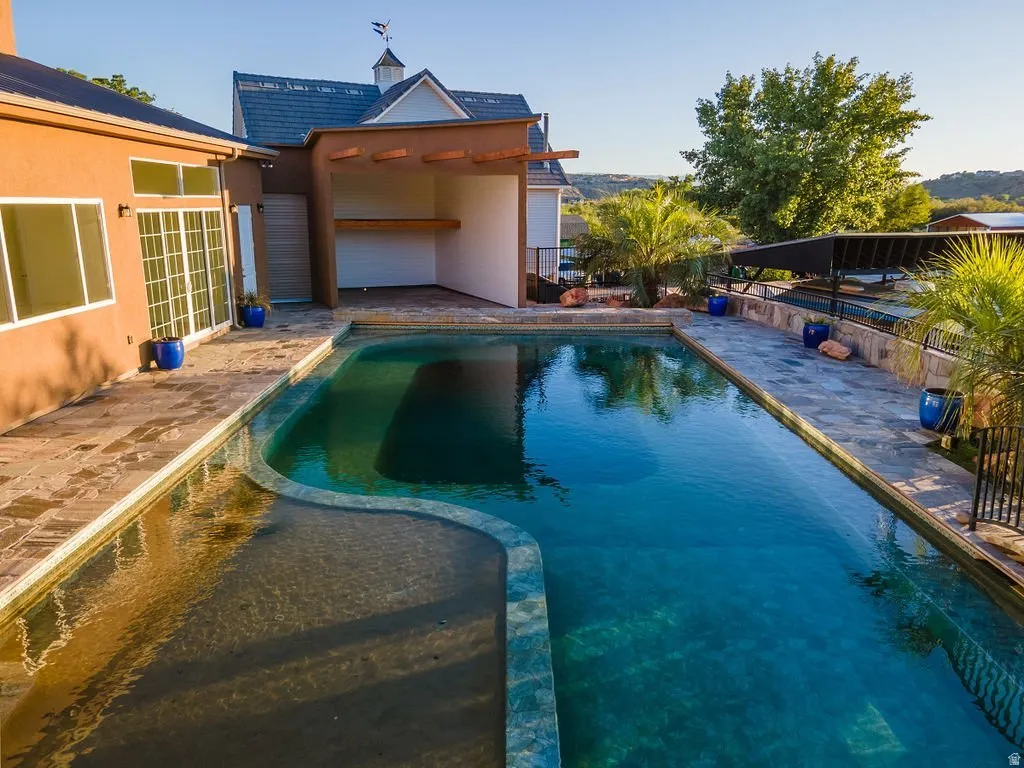 The full backyard — natural pool, cabana, mature planting, open desert light. A private resort behind a gated wall.