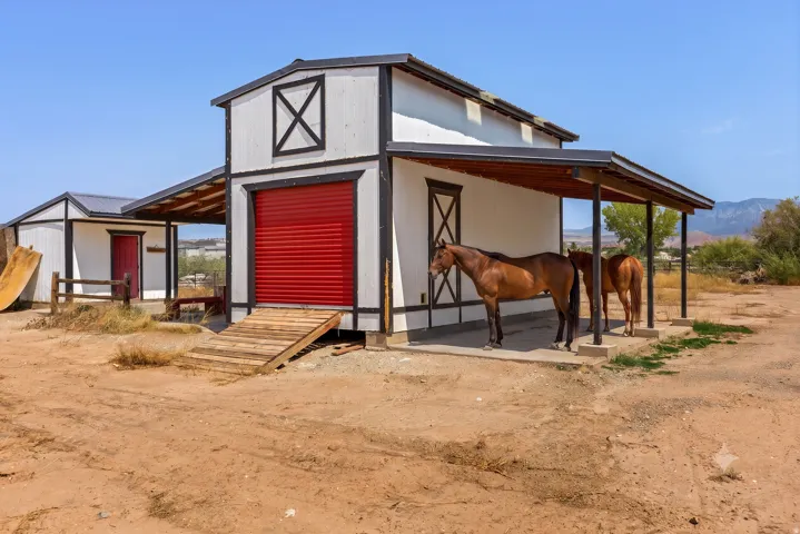 A true two-story barn with roll-up door, covered lean-tos on both sides, and drive-up ramp access to the full upper loft.