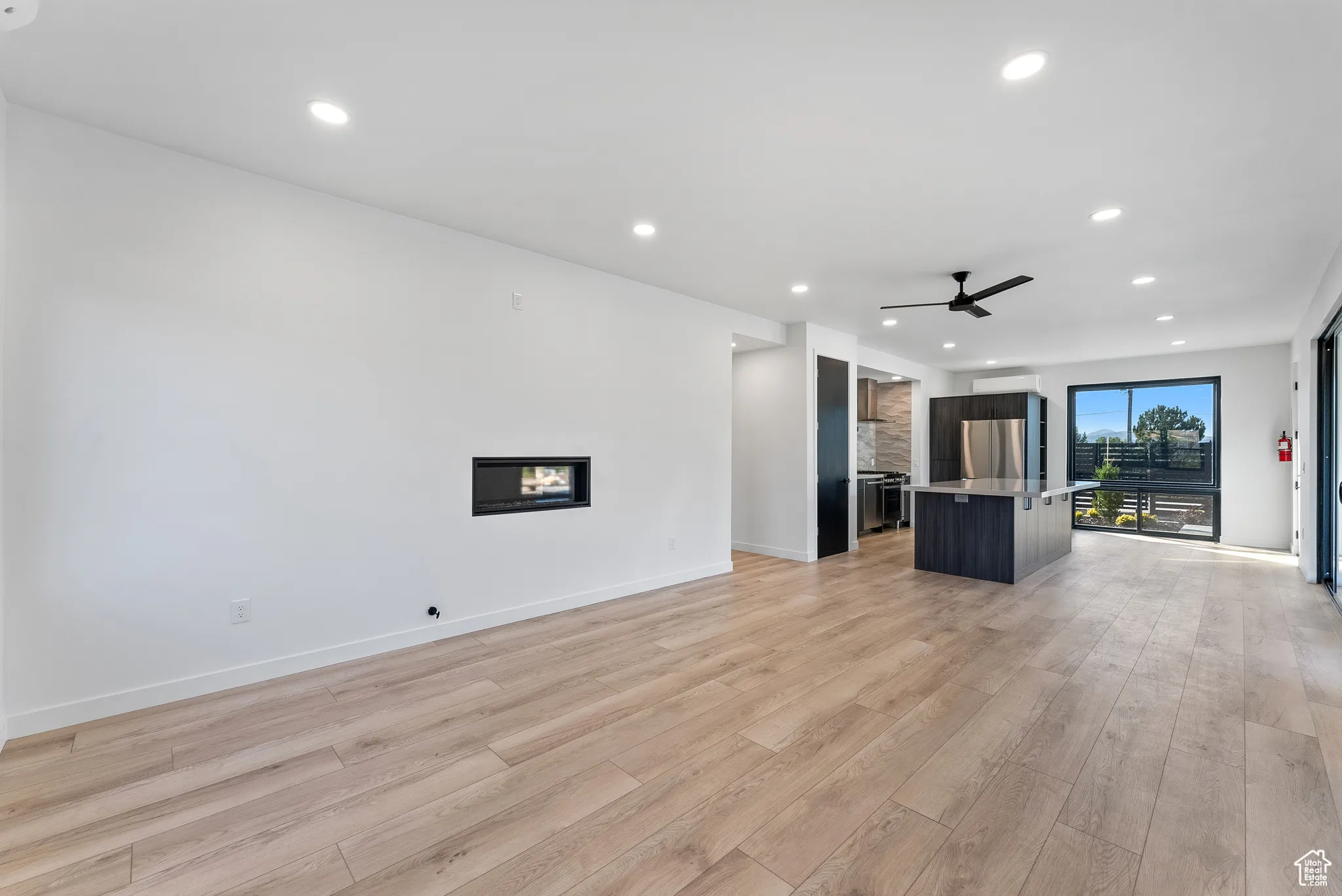 Unfurnished living room with light wood-type flooring and ceiling fan