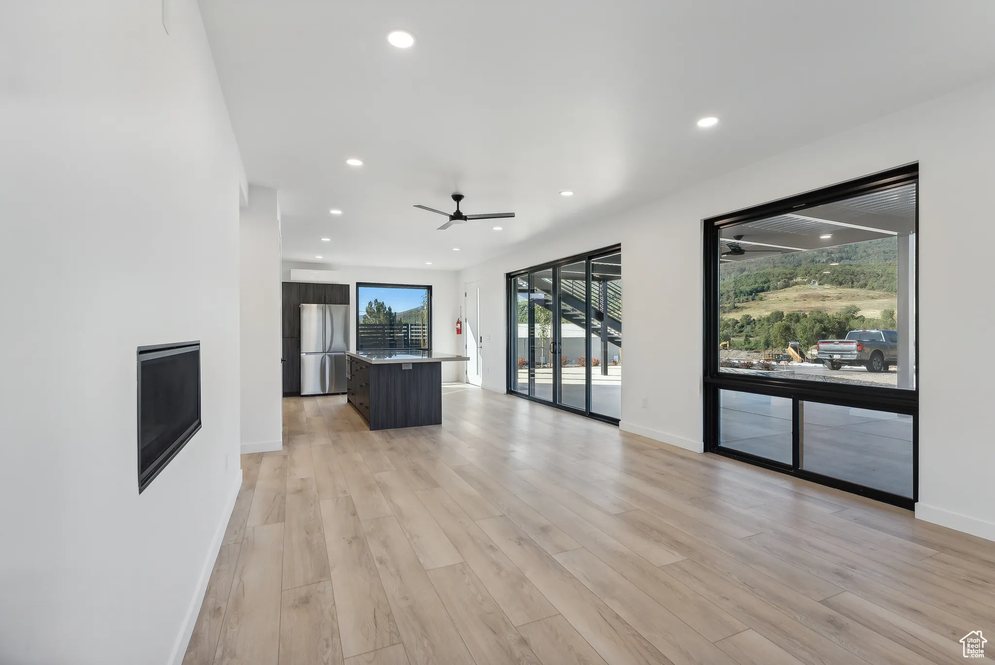 Unfurnished living room featuring ceiling fan and light hardwood / wood-style flooring