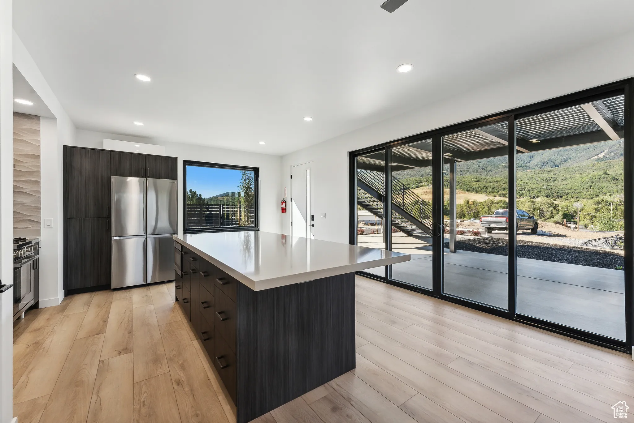 Kitchen with stainless steel refrigerator, light hardwood / wood-style floors, and a center island
