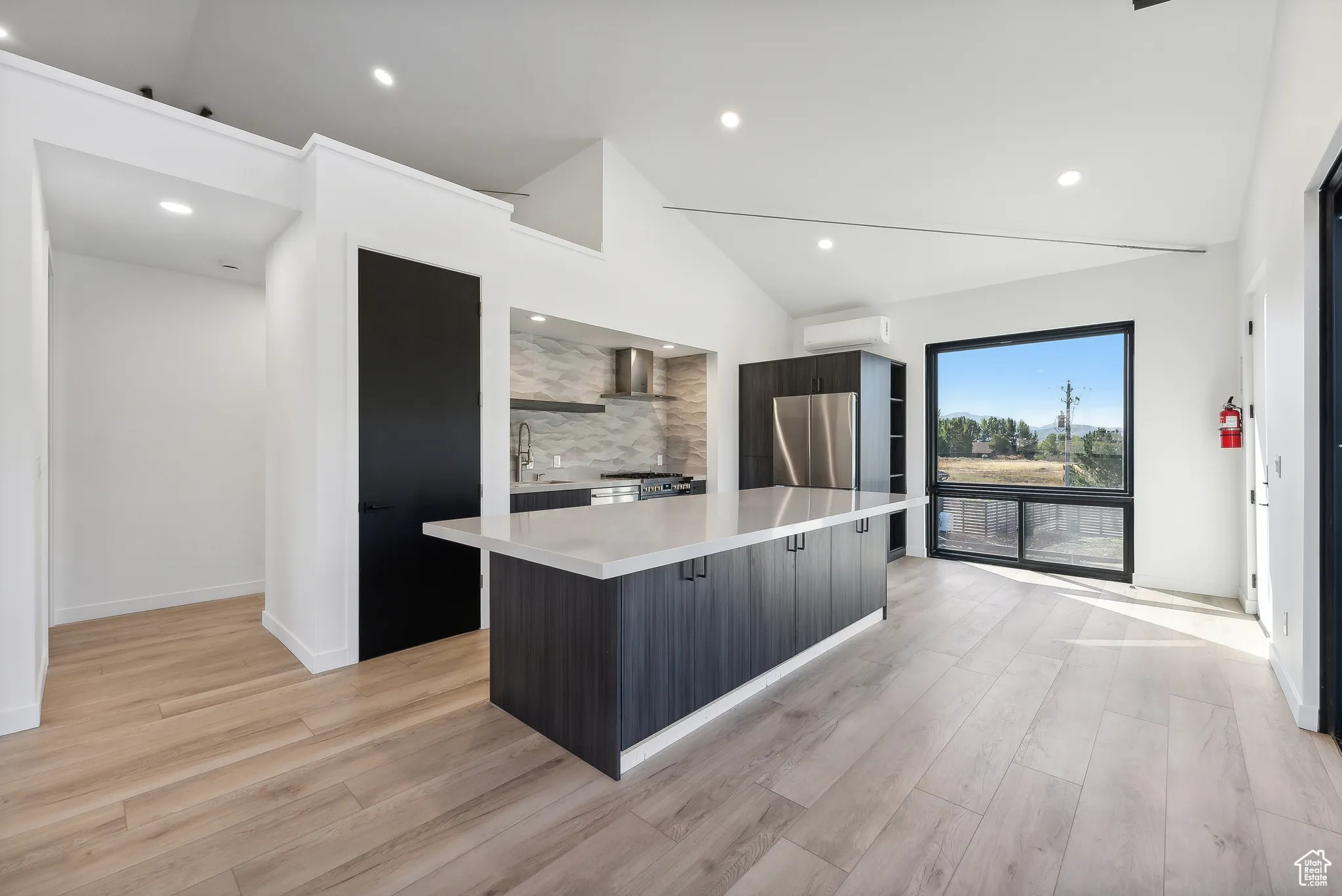 Kitchen featuring high vaulted ceiling, light wood-type flooring, and a kitchen island