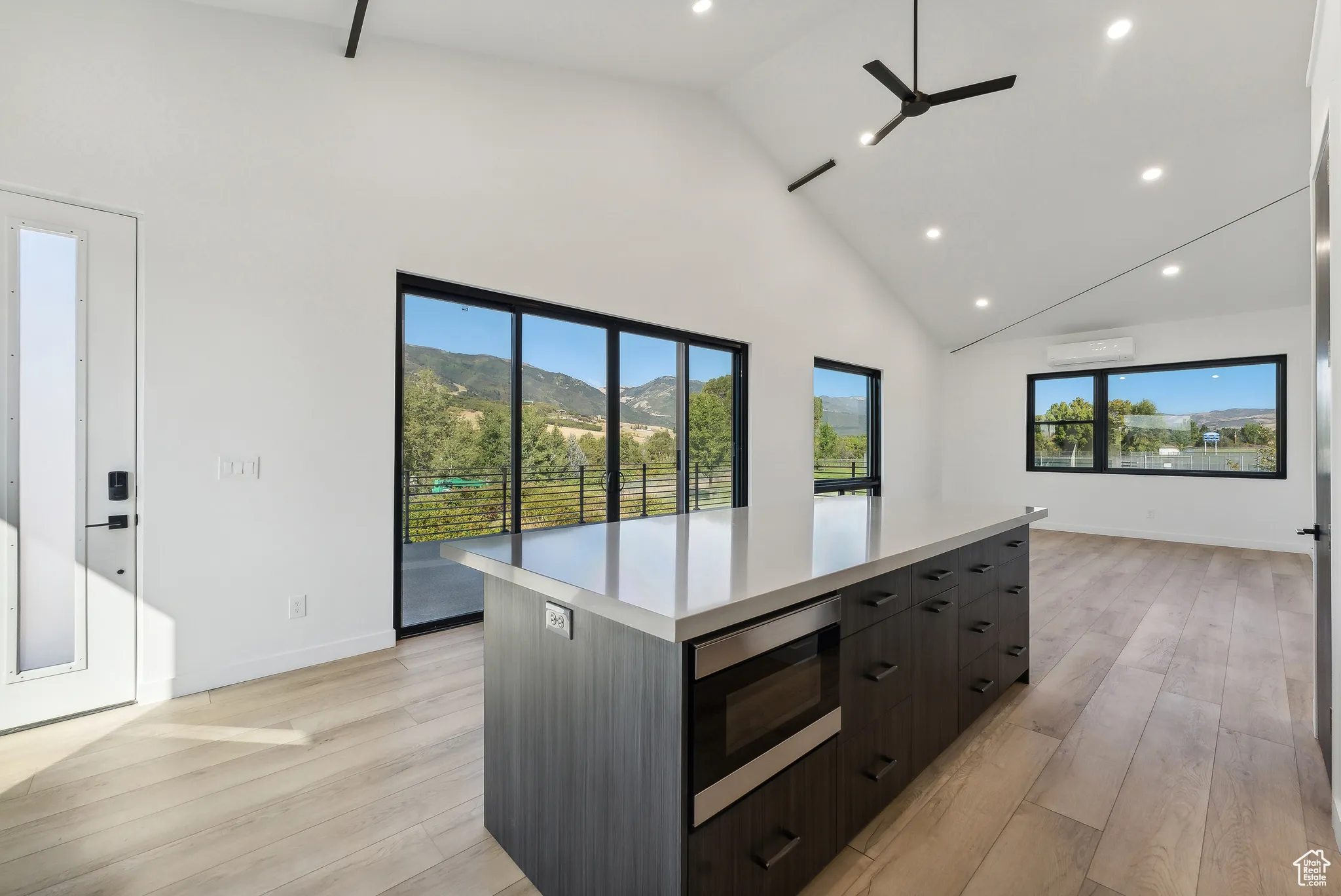 Kitchen with a mountain view, high vaulted ceiling, a spacious island, light wood-type flooring, and stainless steel microwave