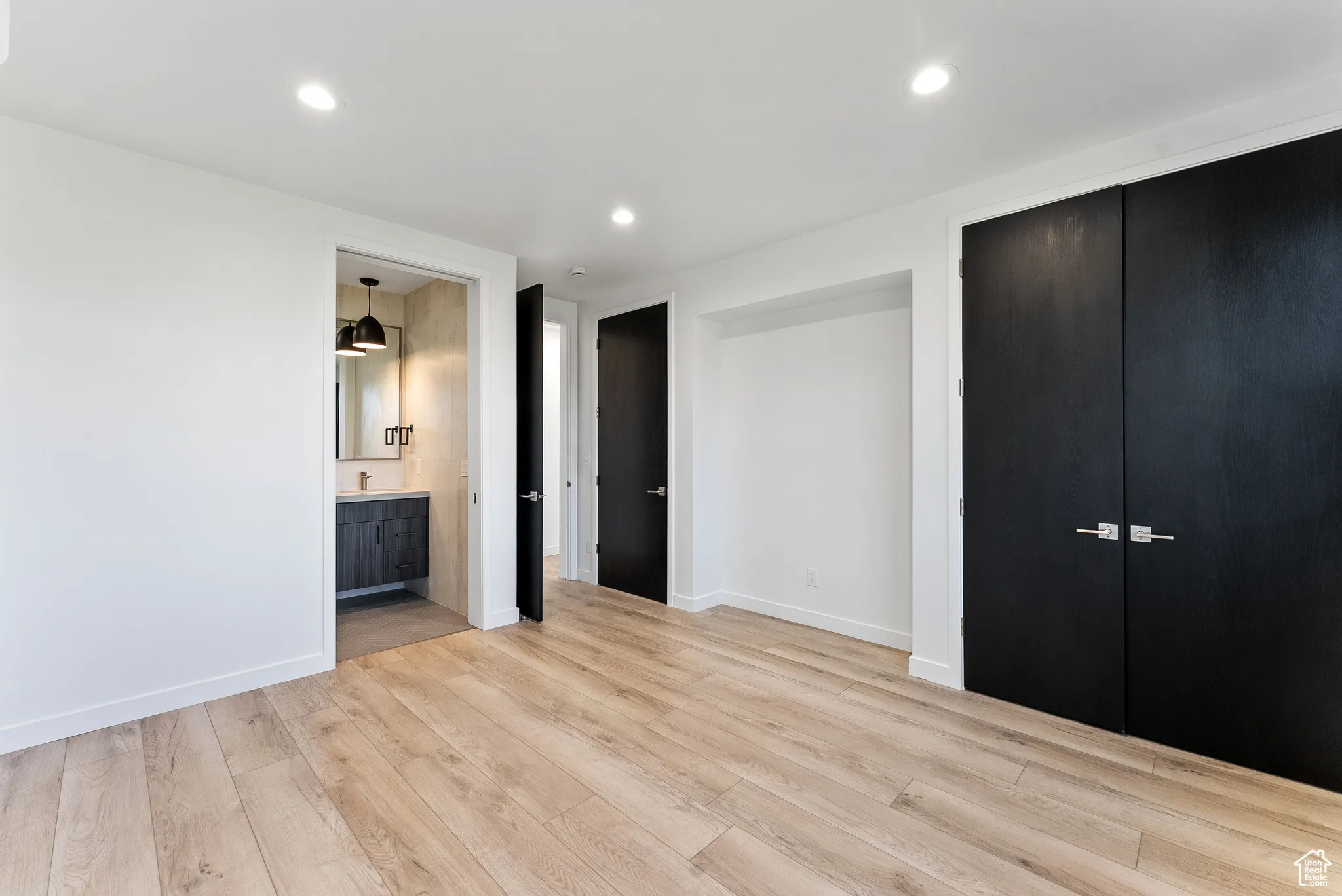 Unfurnished bedroom with a closet, light hardwood / wood-style floors, and ensuite bathroom