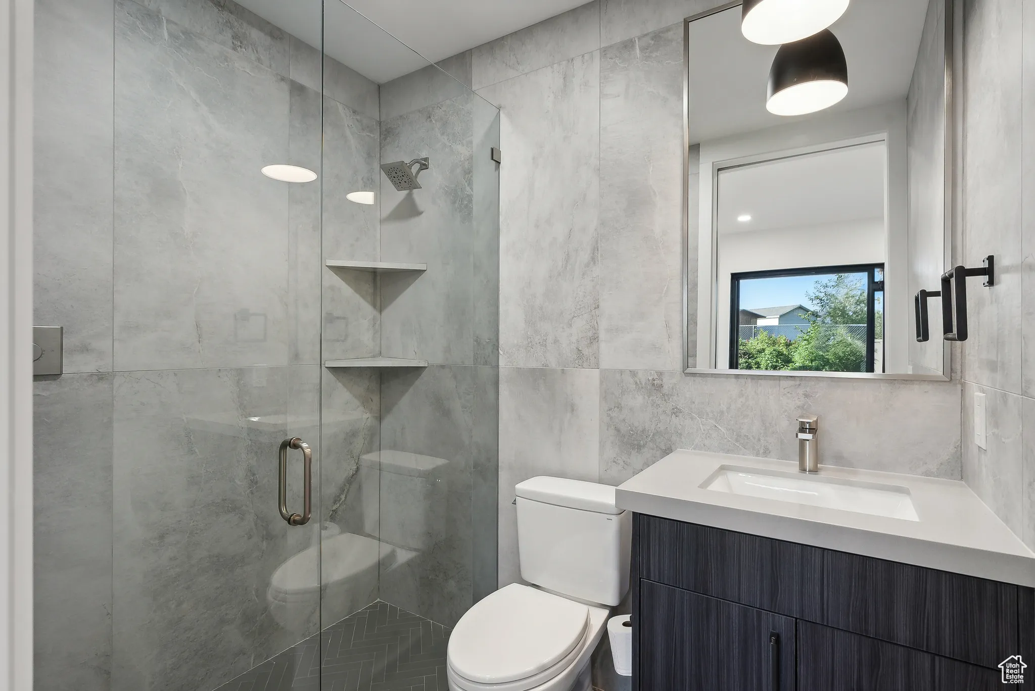 Bathroom with vanity, tile walls, a shower with shower door, and toilet