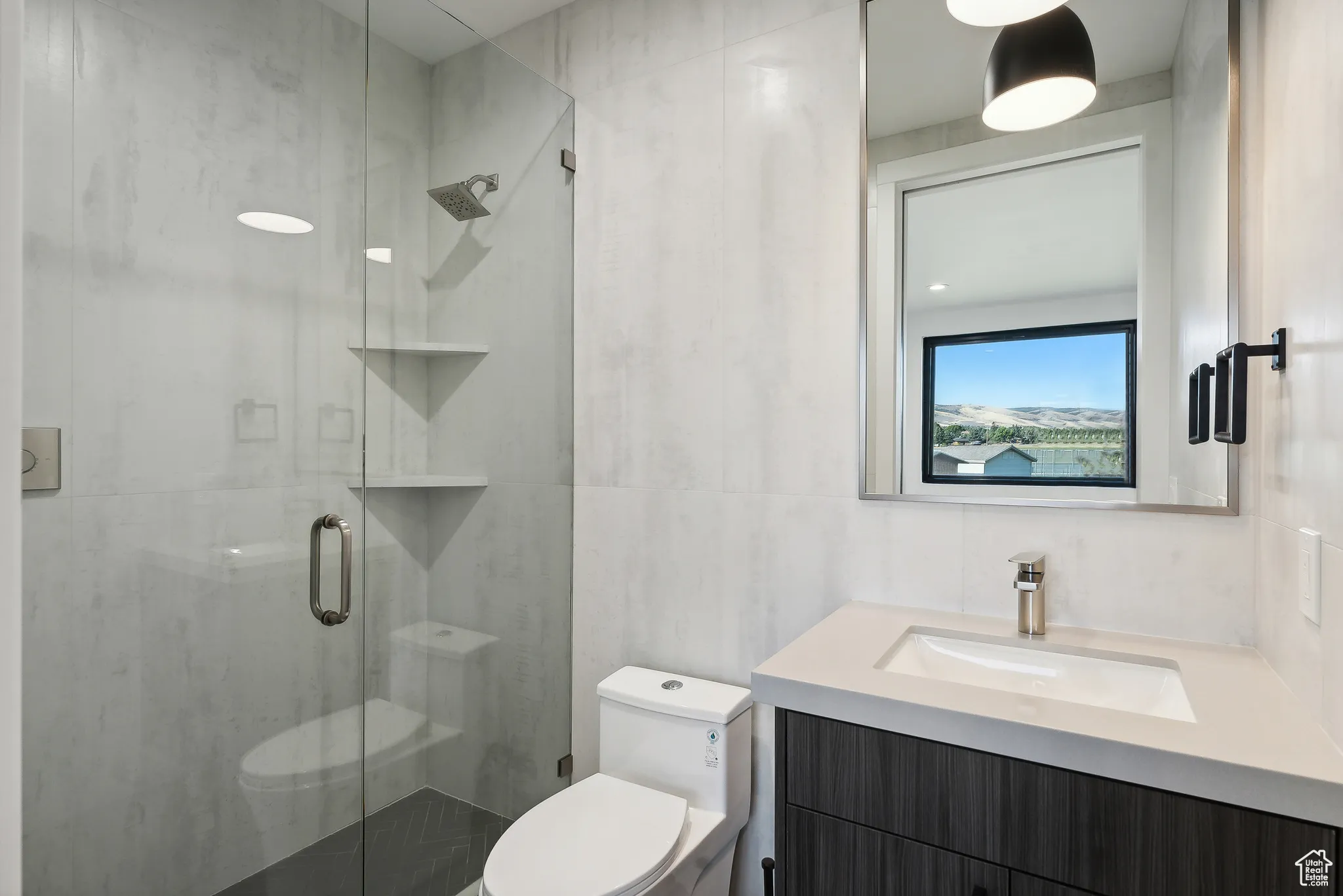 Bathroom featuring tile walls, an enclosed shower, vanity, and toilet