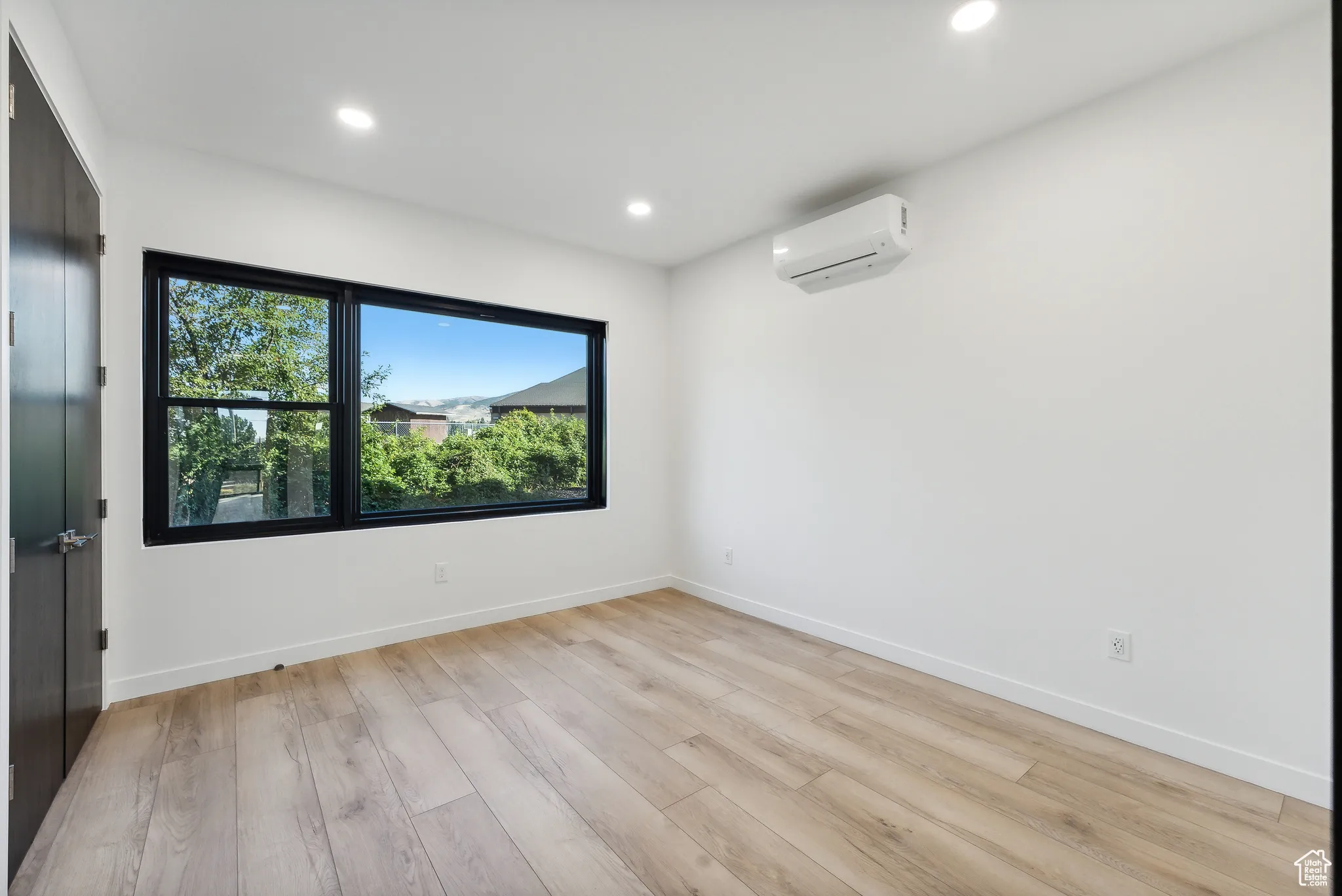 Spare room with light hardwood / wood-style flooring and a wall mounted air conditioner